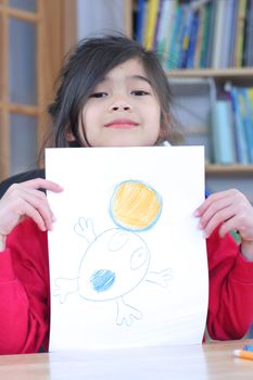 Happy six year old girl showing off drawing.