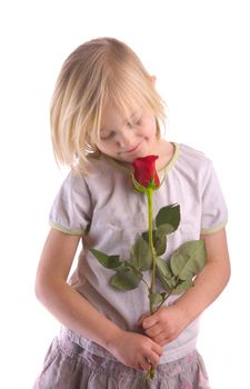 Child smelling red rose against a white background