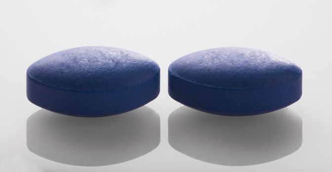 Two blue pills in a close up image.