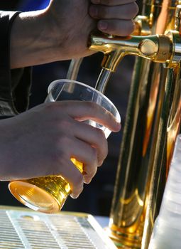 The barman pours beer into a glass