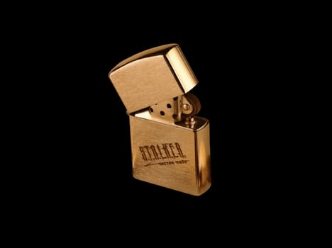 A gold stylish cigarette-lighter is taken picture CU on a black background.                    