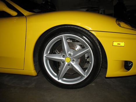 A five star rim on a luxurious, yellow sports coupe.