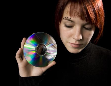 Redhead girl holding a compact disc. Lit with studio lighting, hair light and two umbrelled strobes.