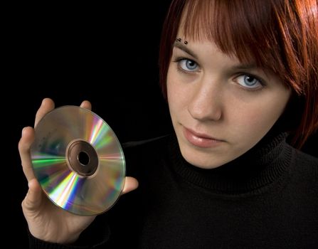Girl holding a compact disc and looking in the camera, beautiful. Her reflection mirrored on the disc surface.
