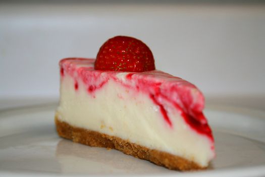 Close up of a strawberry cheesecake on a plate.
