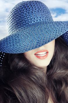 Unrecognizable smiling lady outdoors in blue summer hat