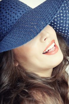 Laughing lady with blue hat on a studio background