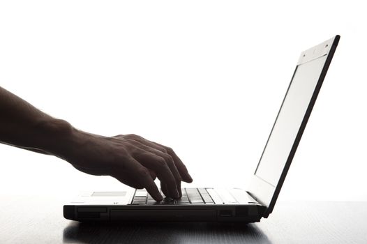 Silhouetted image of someone typing on a laptop computer