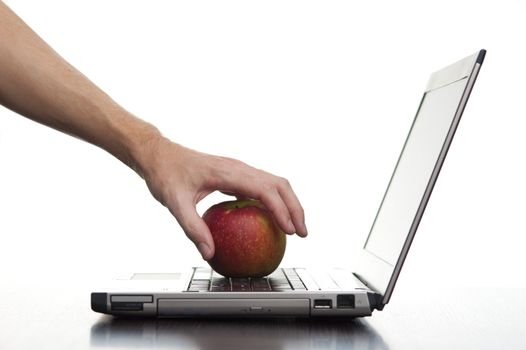 A hand reaching out and taking an apple from a laptop keyboard.