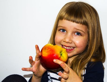 little blonde girl is eating apple