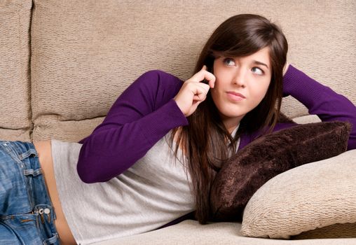 Young girl concerned talking by telephone bad news lying on sofa