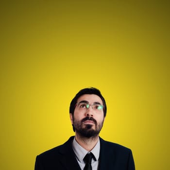 bearded business man looking up on yellow background