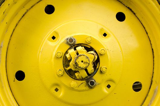 Yellow tractor wheel closeup details bolts nuts holes