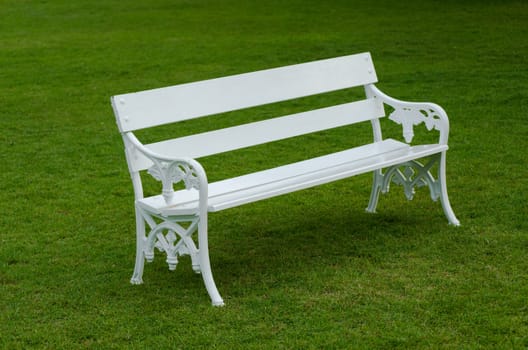 White Bench on green lawn in the garden