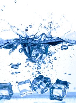 ice cubes dropped into water with splash on white