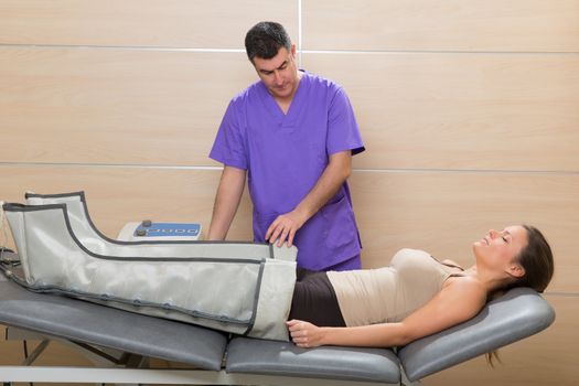 Doctor checking legs pressotherapy machine on woman patient in hospital bed