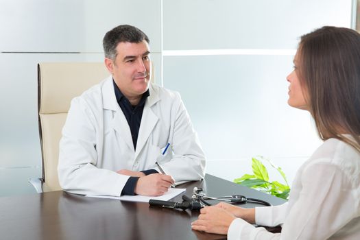Doctor man and patient woman on hospital office talking on desk