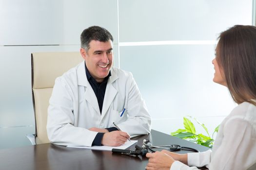 Doctor man and patient woman on hospital office talking on desk