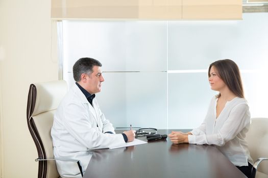 Doctor man and patient woman on hospital office talking on desk