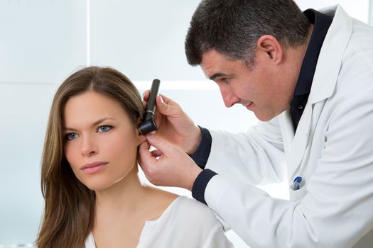 Doctor ENT checking ear with otoscope to woman patient at hospital