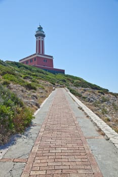Concept of direction with this road and lighthouse. Copy space on blue background.