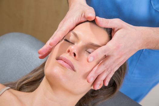 facial massage relaxing therapy on woman face with therapist hands