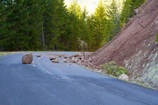 This national forest road is blocked by a land slide of rock and debris to where it is a hazard for drivers in cars.