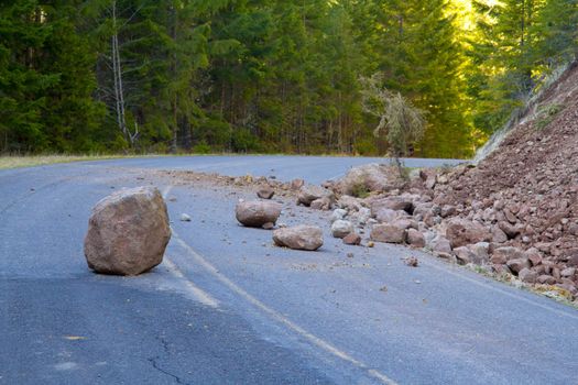 This national forest road is blocked by a land slide of rock and debris to where it is a hazard for drivers in cars.