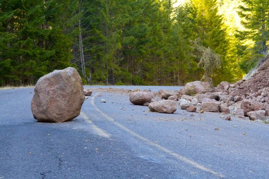 This national forest road is blocked by a land slide of rock and debris to where it is a hazard for drivers in cars.