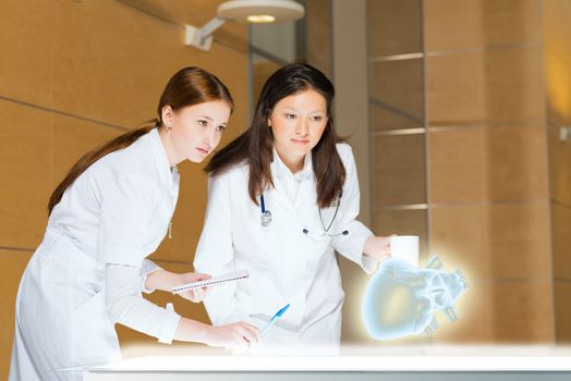 two doctors stand near glowing table discussing. projected objects on a desk