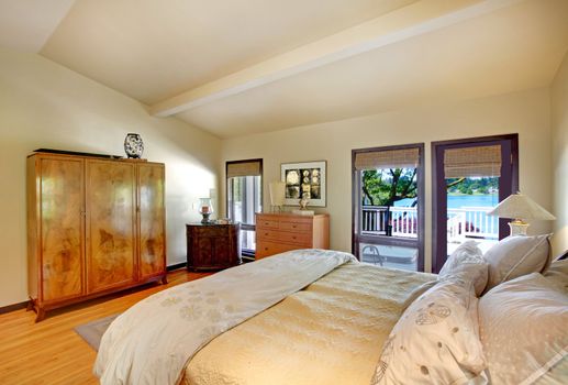 Modern luxury bedroom with bed, dresser and lake view.