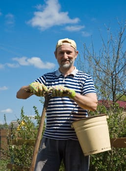 A man with a rake and a bucket in the garden