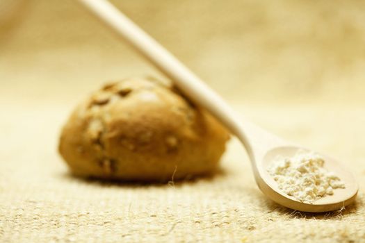 bun with beans and a spoon of flour on linen fabric