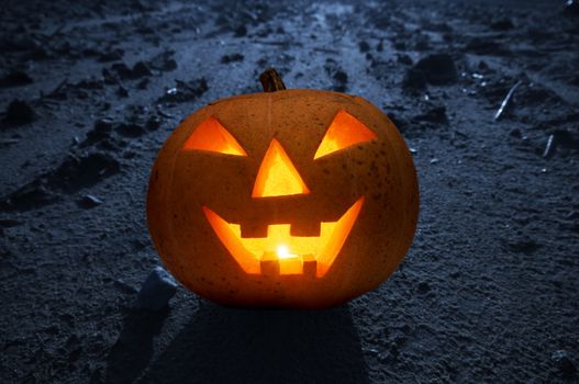 Halloween glowing and smiling pumpkin face on dark land with moonlight at night