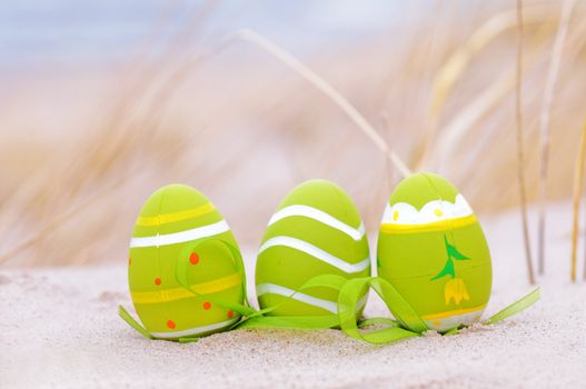 Easter decorated eggs on sand. Beach and ocean in the background