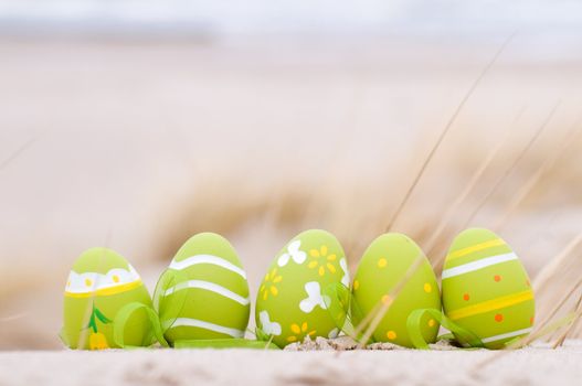 Easter decorated eggs on sand. Beach and ocean in the background