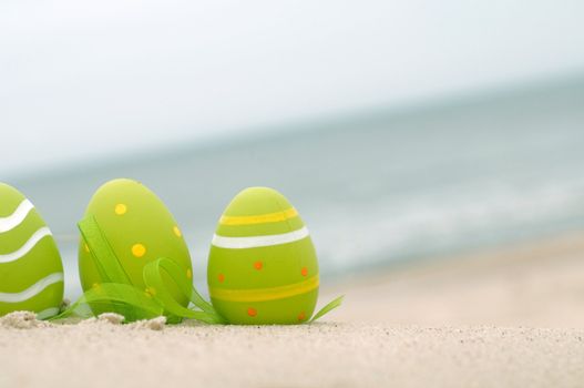 Easter decorated eggs on sand. Beach and ocean in the background