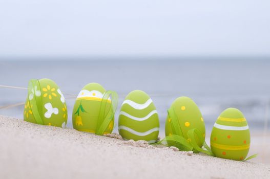 Easter decorated eggs on sand. Beach and ocean in the background