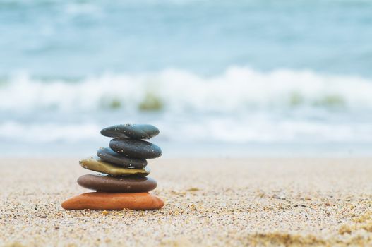 Stack of beach stones on sand. Ocean in the background