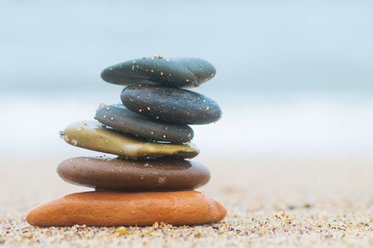 Stack of beach stones on sand. Ocean in the background