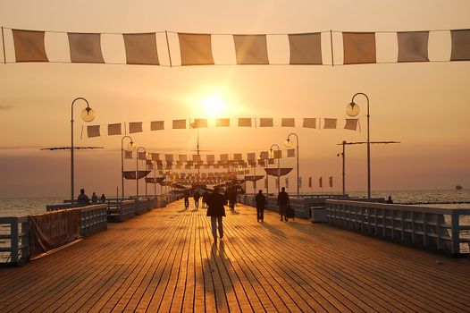 People walking on pier during sunrise