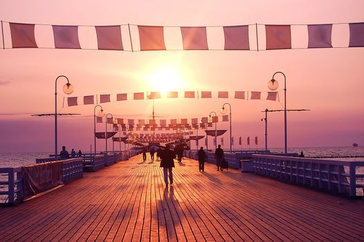 People walking on pier during sunrise