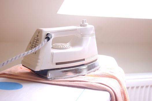 Electric iron on towel in bright room