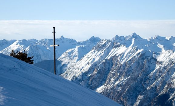 Winter mountains view with cross facing mountains