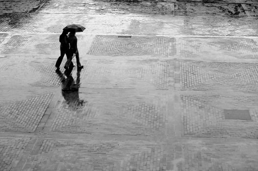 Two women with umbrella walking in rain 