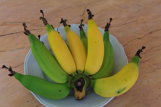 Fresh Bananas on white disk with light brown Background