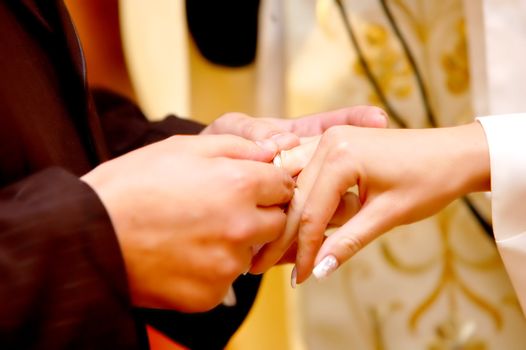 Wedding ceremony, Groom put a ring on bride hand.