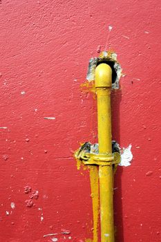 yellow iron pipe on the red wall