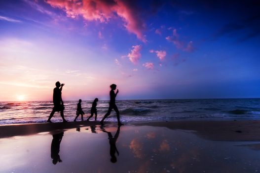 Family walk on the beach at sunset