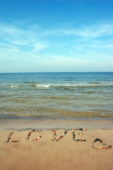 Word LOVE on beach sand, made from rocks